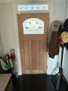 Interior view of the installed wood entry door with decorative glass and white trim